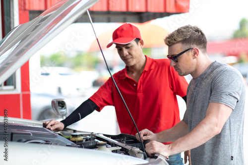 Professional car mechanic checking and maintenance service in gas station. Power to drive vehicles and gas station pump concept.