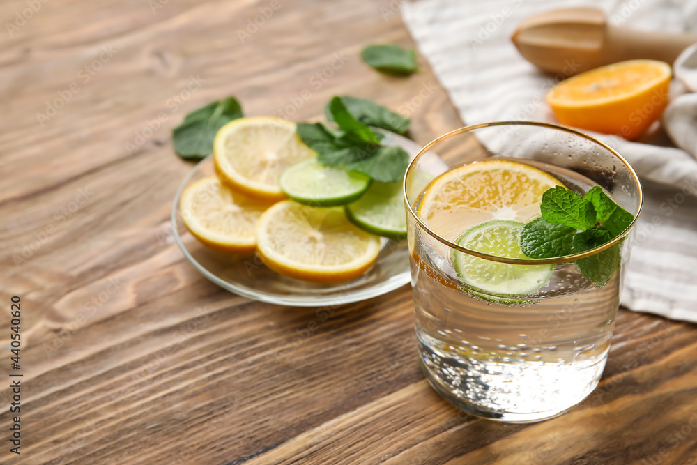 Glass of healthy lemonade and citrus fruits on wooden background Glass of healthy lemonade and citrus fruits on wooden background