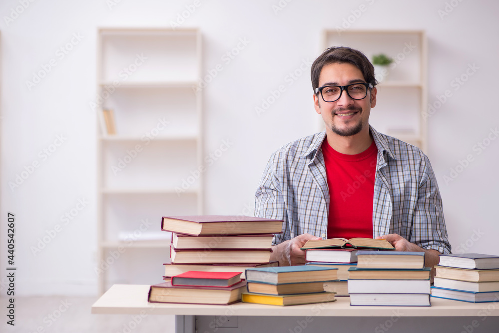 Young male student and too many books in the classroom