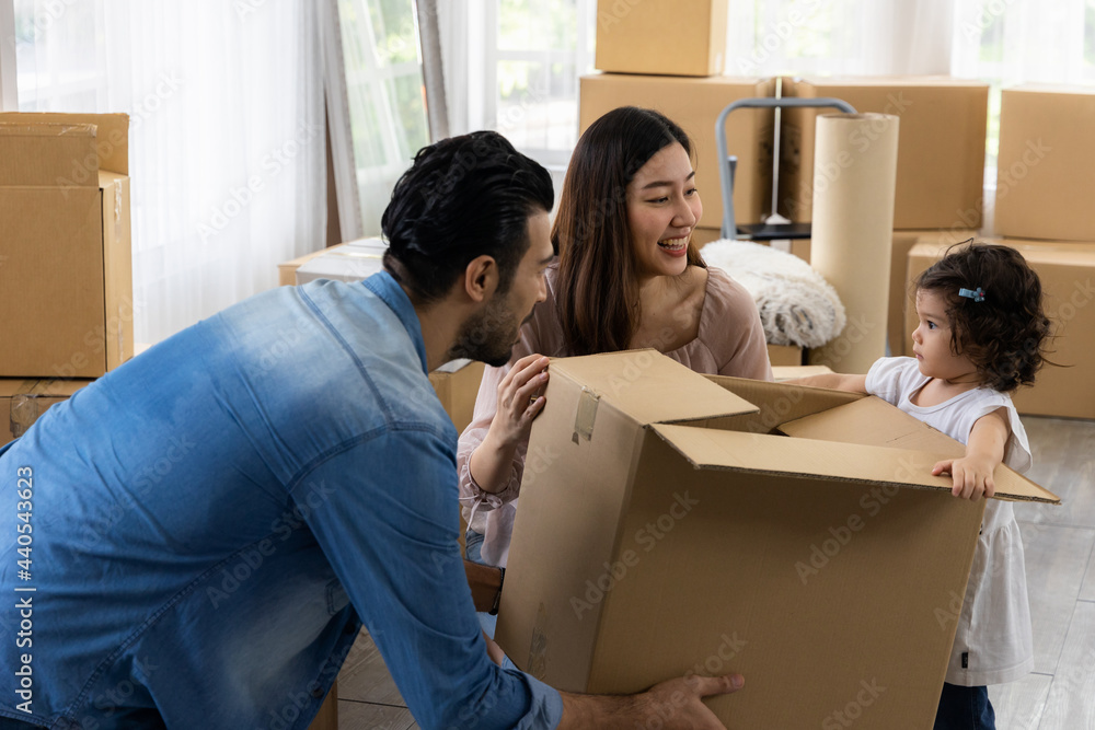 Cute daughter with parent are holding large paper box. Happy family in living room. Moving new house a lot of parcel. Father mother and daughter relax together at new home. Cute daughter with parent are holding large paper box. Happy family in living room. Moving new house a lot of parcel. Father mother and daughter relax together at new home.