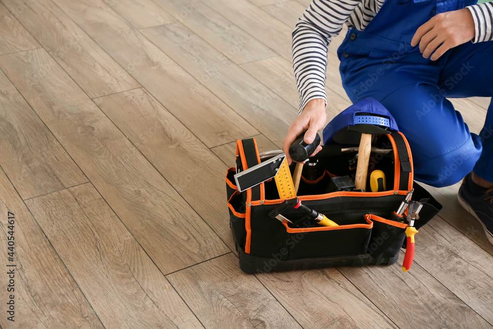 Obraz premium Carpenter during installing of laminate flooring in room