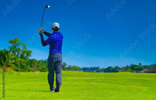 Man playing golf on a golf course in the sun, Golfers hit sweeping golf course in the summer 