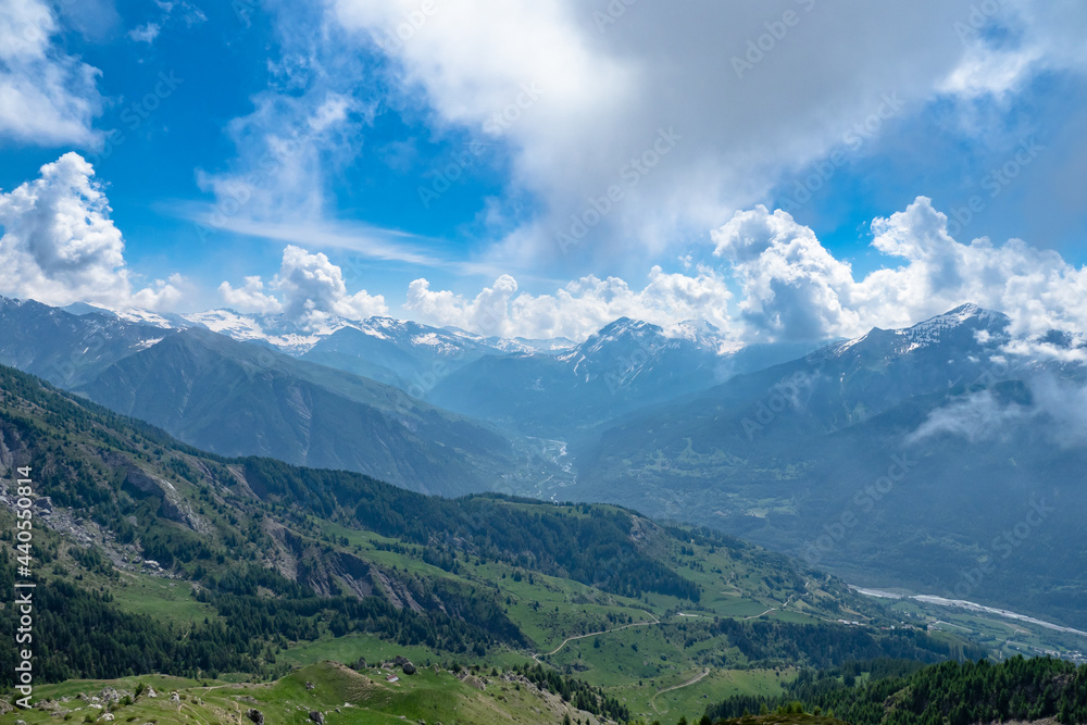 Fototapeta premium Springtime scenic view of the mountains in the Alps with emerging plant life and diminishing snow capped peaks