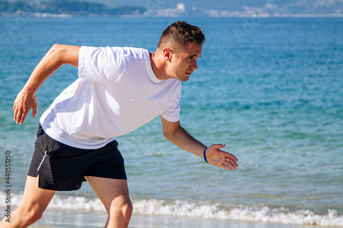 young man in starting position for jogging on the beach
