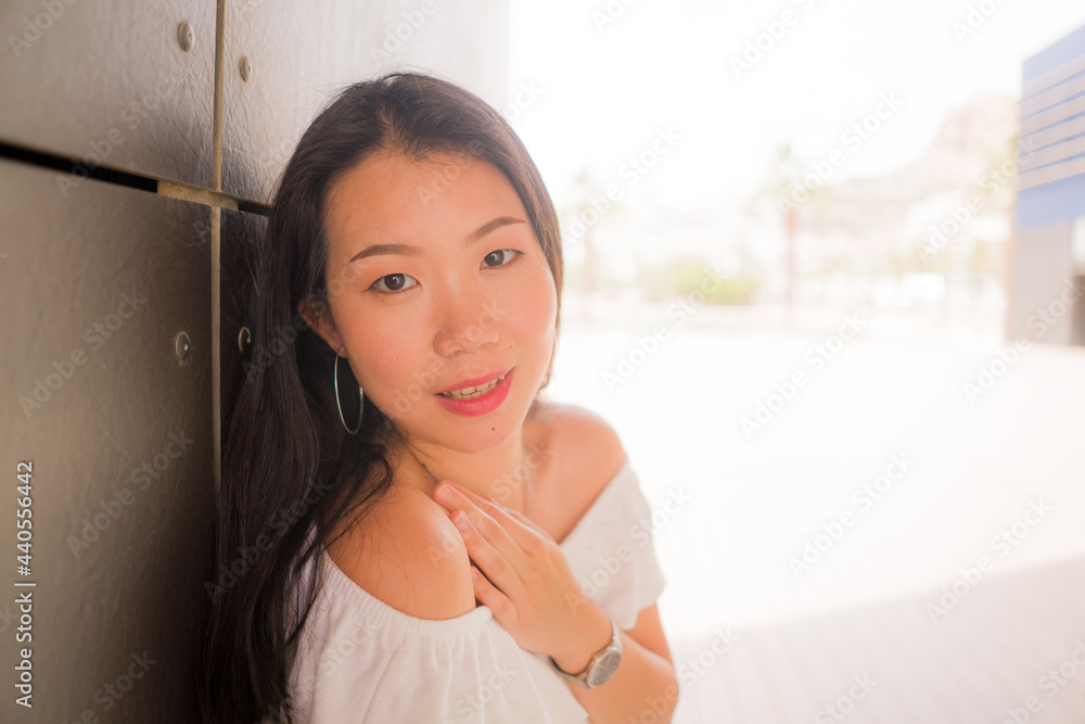 casual  lifestyle portrait of young beautiful and happy Asian Chinese woman in white summer dress enjoying outdoors looking at camera smiling cheerful