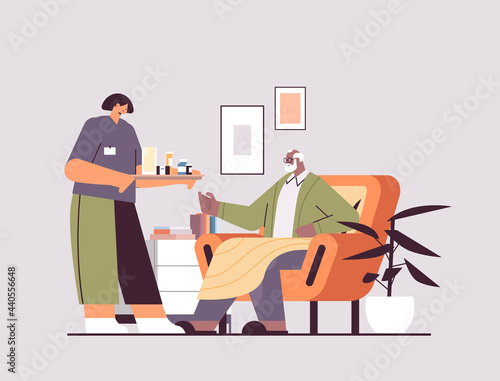 female nurse or volunteer bringing pills to elderly man patient home care services healthcare and social support