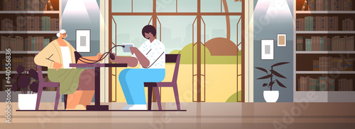 nurse or volunteer checking blood pressure to elderly woman home care services healthcare and social support