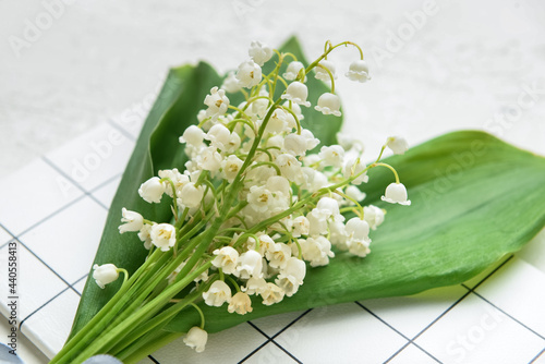 Beautiful lily-of-the-valley flowers and notebook on light background, closeup