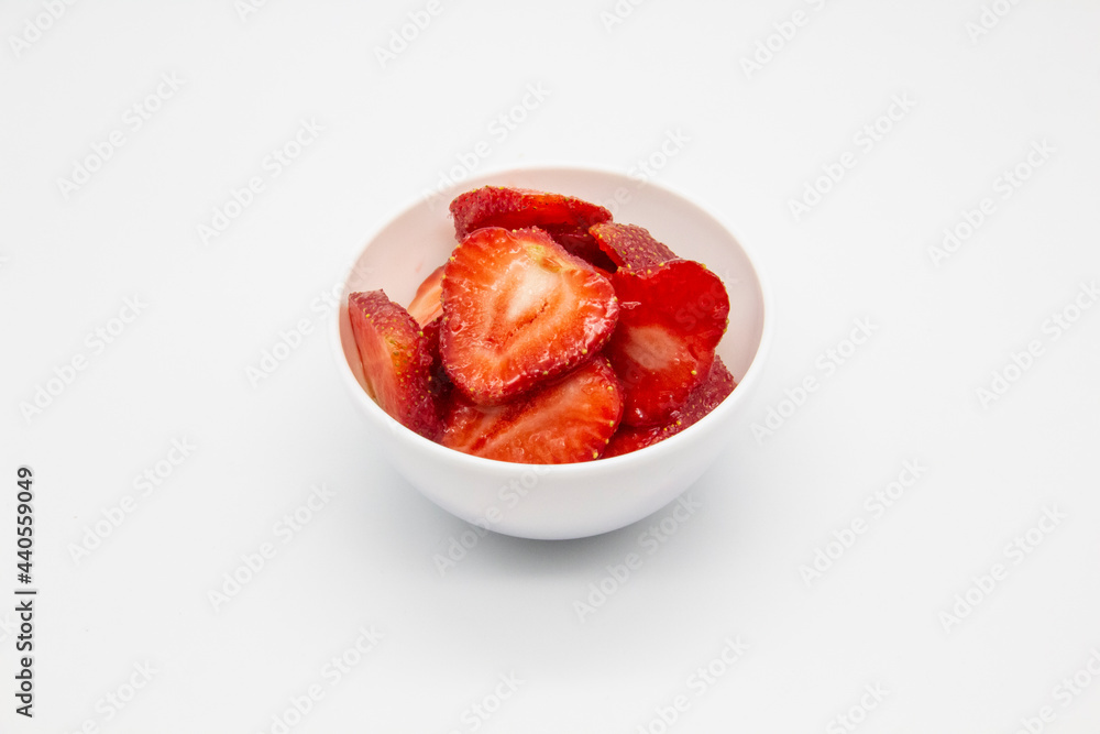 Sliced strawberries in a white plate against white background. Sliced strawberries in a white plate against white background.