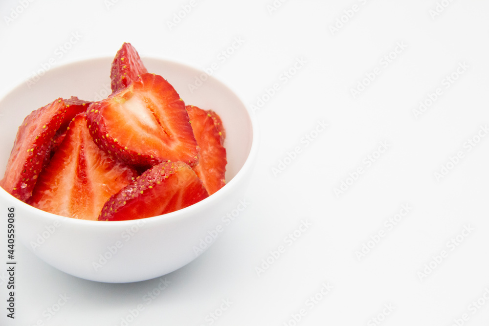 Sliced strawberries in a white plate against white background. Sweet berry dessert with copy space. Sliced strawberries in a white plate against white background. Sweet berry dessert with copy space.