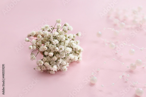 Beautiful gypsophila boutonniere and beads on color background