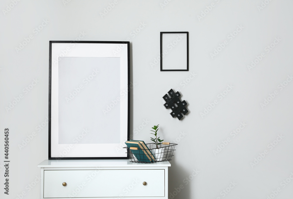 Interior of modern stylish room with chest of drawers and blank photo frames Interior of modern stylish room with chest of drawers and blank photo frames