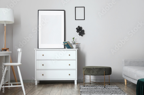 Interior of modern stylish room with chest of drawers and blank photo frame