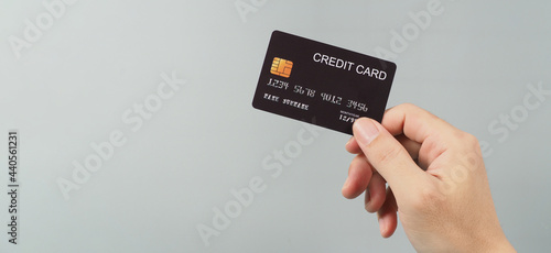Hand is holding black credit card isolated on grey background. photo