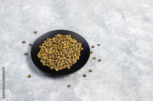Green peppercorns in a small bowl and spoon.