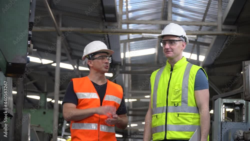 Engineer and technician manager talking together with tablet controlling and operate control panels heavy machine in the industrial plant while the workers are working in the Industrial factory . Engineer and technician manager talking together with tablet controlling and operate control panels heavy machine in the industrial plant while the workers are working in the Industrial factory .
