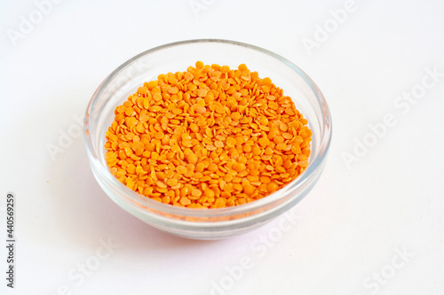 Red lentils in a glass bowl isolated on a white background