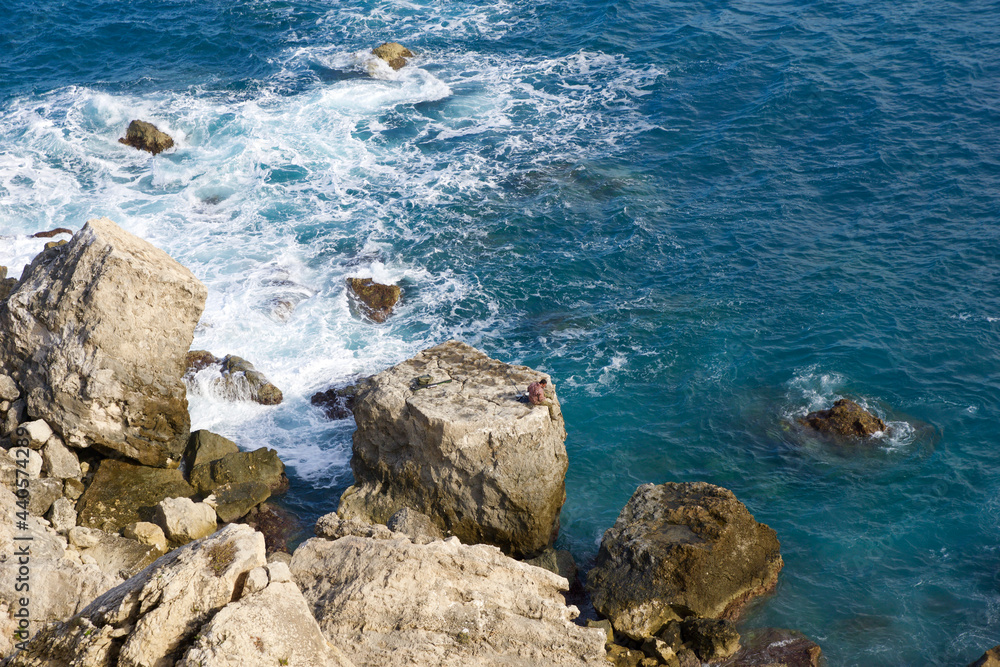 MELLIEHA, MALTA - 01 JAN, 2020: A man sitting on a rock near the ocean on the island of Malta during calm sea