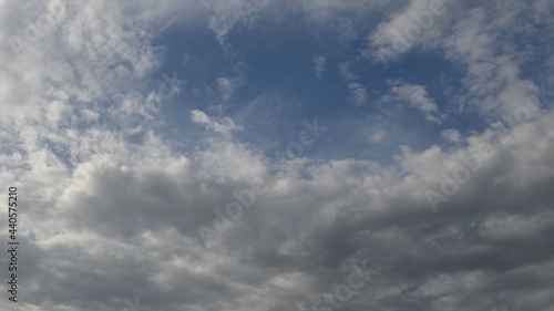 Azure blue sky with white fluffy cumulus clouds floating in wind. Serene cloudscape of summer weather. Altocumulus and cirrocumulus types of clouds