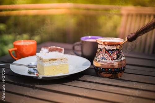 Rustic breakfast. Wooden coffee table with coffee cups, cezve, lake Bled cream cake photo