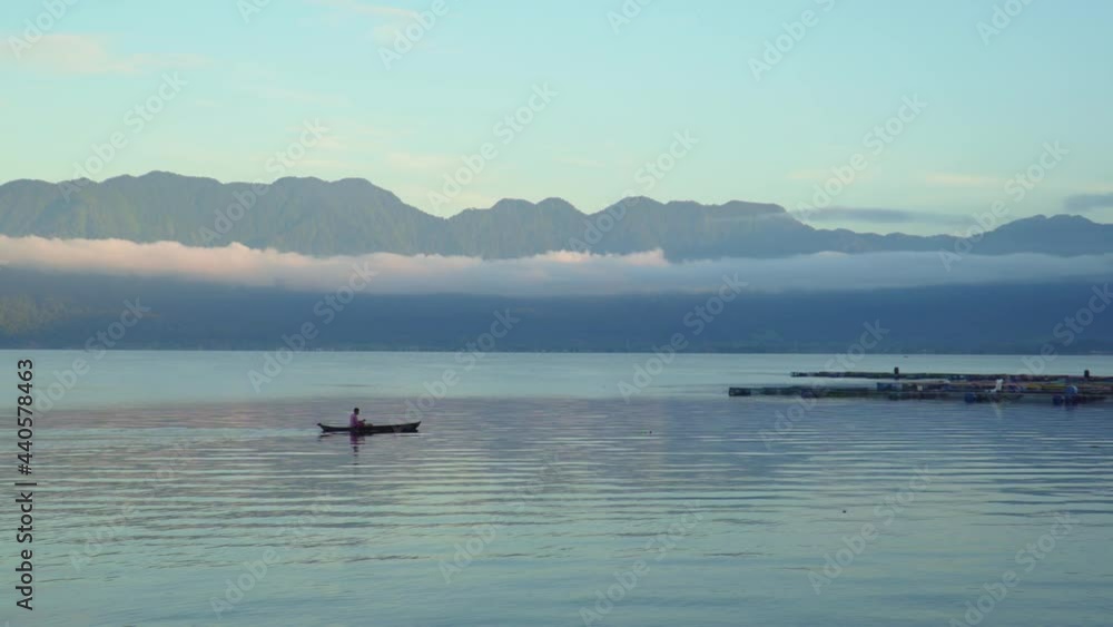 Beautiful landscape of Maninjau Lake, Indonesia at golden hour in the morning with a fishing boat sailing over. The landscape of West Sumatra, Indonesia nature. Beautiful landscape of Maninjau Lake, Indonesia at golden hour in the morning with a fishing boat sailing over. The landscape of West Sumatra, Indonesia nature.