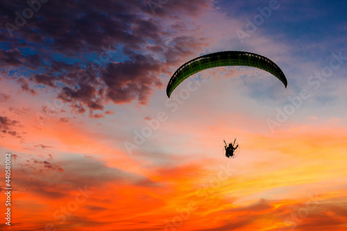 Skydiving sunset landscape of parachutist flying in soft focus. Para-motor flying silhouette with sun set. Silhouette of paraglider flying in the evening sky with sunset.