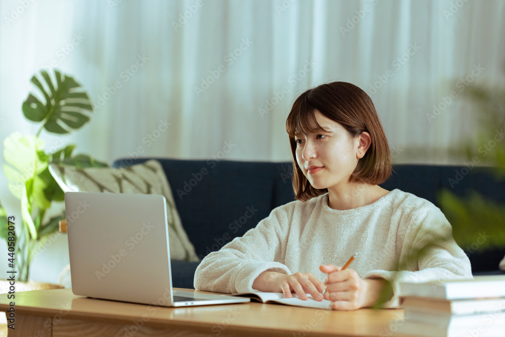 リビングでオンライン学習中の若い女性 リビングでオンライン学習中の若い女性
