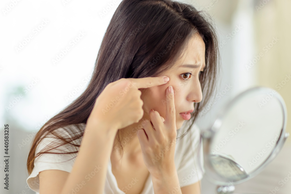 Woman looking at mirror and checking the acne problem at home Woman looking at mirror and checking the acne problem at home