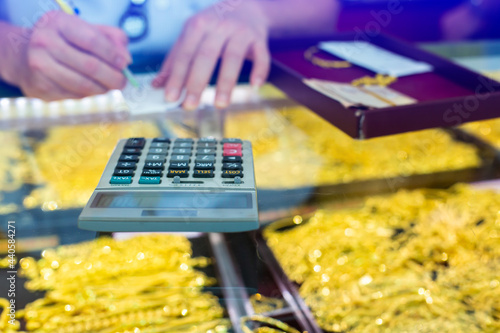 Obraz na płótnie Selective focus to calculator to calculate the purchase of gold jewelry with blurry gold and bracelet in the showcase at gold shop