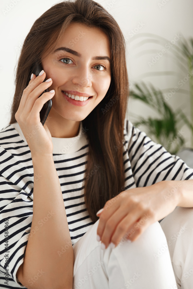 Vertical shot of brunette girl talking on mobile phone, calling someone on smartphone and smiling, having casual conversation Vertical shot of brunette girl talking on mobile phone, calling someone on smartphone and smiling, having casual conversation
