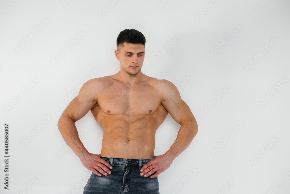 A young sexy athlete with perfect abs poses in the studio topless in jeans on the background. Healthy lifestyle, proper nutrition, training programs and nutrition for weight loss. A young sexy athlete with perfect abs poses in the studio topless in jeans on the background. Healthy lifestyle, proper nutrition, training programs and nutrition for weight loss.