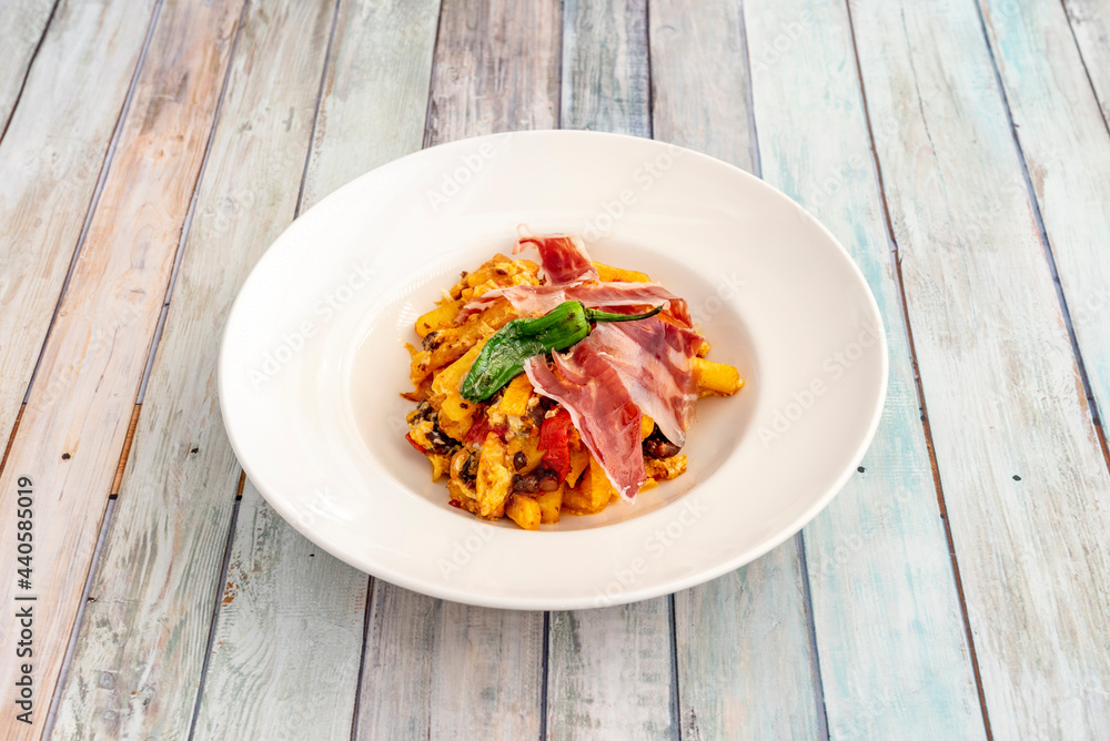 Typical Spanish dish of broken eggs, with homemade fried potatoes, Padrón peppers and slices of acorn-fed Iberian ham Typical Spanish dish of broken eggs, with homemade fried potatoes, Padrón peppers and slices of acorn-fed Iberian ham