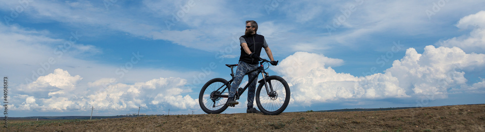 Conquering mountain peaks by cyclist in shorts and jersey on a modern carbon hardtail bike with an air suspension fork .