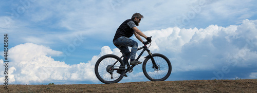 Conquering mountain peaks by cyclist in shorts and jersey on a modern carbon hardtail bike with an air suspension fork .