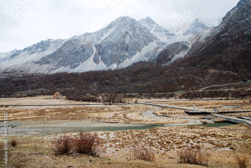 Landscape of Luorong Pasture with wood bridge cross the waterway that way for trekking to see milk lake at Daocheng County,Sichuan Province, China -hikes to epic mountains and adventurous backpacking