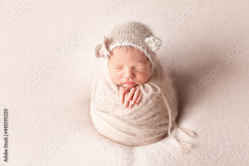 first newborn photo session. baby on a beige blanket in a hat with ears. baby wrapped in a cocoon