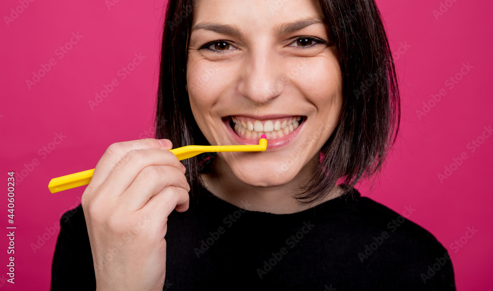 Beautiful happy young woman with single tufted toothbrush on blank pink background Beautiful happy young woman with single tufted toothbrush on blank pink background