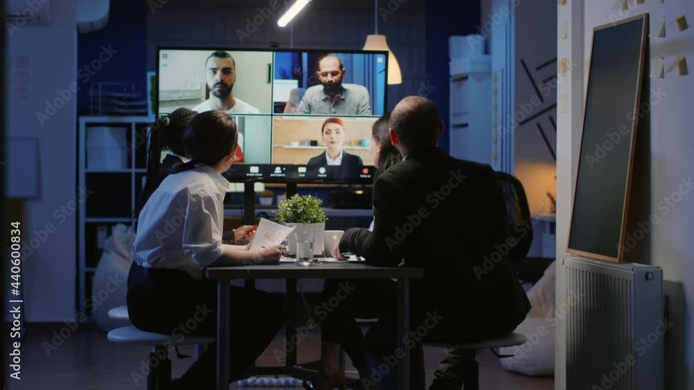 Diverse group of business teamwork discussing with remote coworkers during online videocall conference. Multi ethnic businesspeople working in meeting room late at night planning company presentation