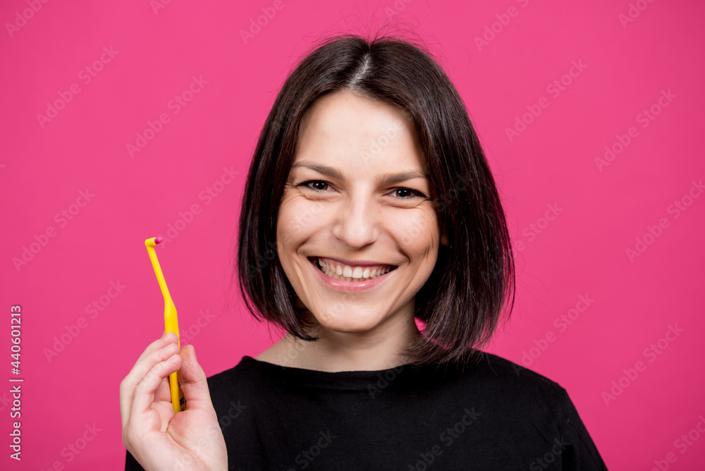 Beautiful happy young woman with single tufted toothbrush on blank pink background Beautiful happy young woman with single tufted toothbrush on blank pink background