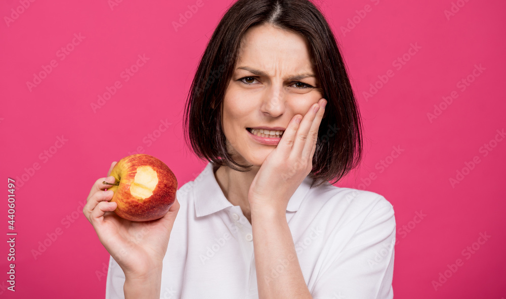 Beautiful young woman bites a big apple and has a toothache Beautiful young woman bites a big apple and has a toothache