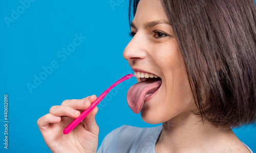 Wallpaper Mural Beautiful happy young woman with tongue scraper on blank blue background Torontodigital.ca