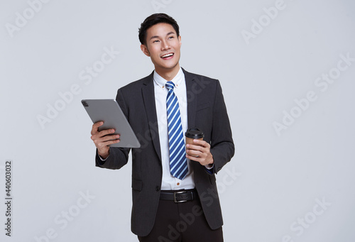 Handsome and friendly face asian businessman smile in formal suit his using tablet on white background studio shot.