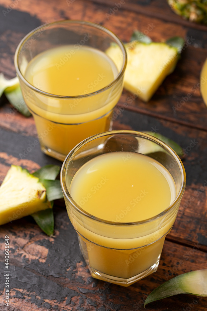 Freshly squeezed Pineapple juice in glass jug and two glasses on rustic wooden table Freshly squeezed Pineapple juice in glass jug and two glasses on rustic wooden table