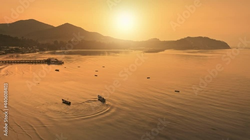 Orange sunset over island sea bay aerial view. Beautiful calm place to stay. Water boat taxi at sun tropical resort. Mountains surround beach. Gastronomic Asia tour. Ban Chalok Lam, Phangan, Thailand. photo
