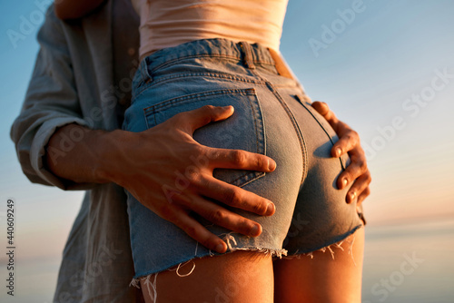 Young caucasian man holding woman buttocks at sunset