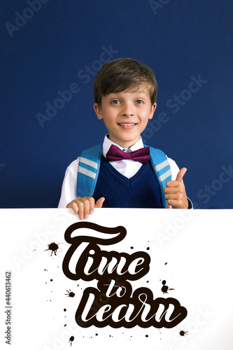 Close-up of a smiling, laughing, happy, funny teenage boy showing thumb up isolated on blue background. lettering Time to learn