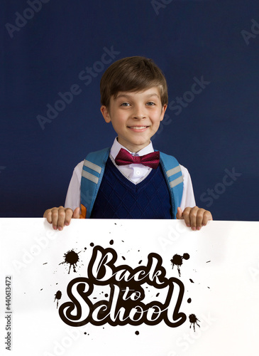 Close-up of a smiling, laughing, happy, funny teenage boy showing isolated on blue background. lettering Back to school