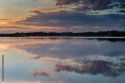 Nice landscape with sunset on lake. View of sky reflection on water and birds flying in the sky.
