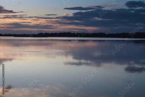 Nice landscape with sunset on lake. View of sky reflection on water and birds flying in the sky.
