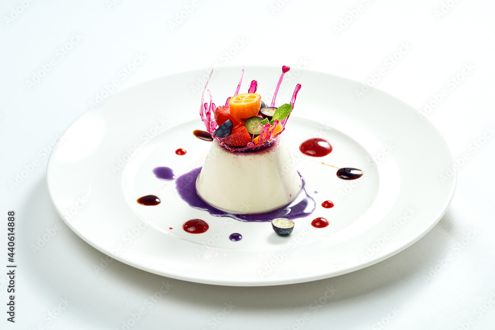 Delicious dessert - vanilla mousse with berry filling and caramel and berry decoration in a white plate. Isolated on white background. Delicious dessert - vanilla mousse with berry filling and caramel and berry decoration in a white plate. Isolated on white background.
